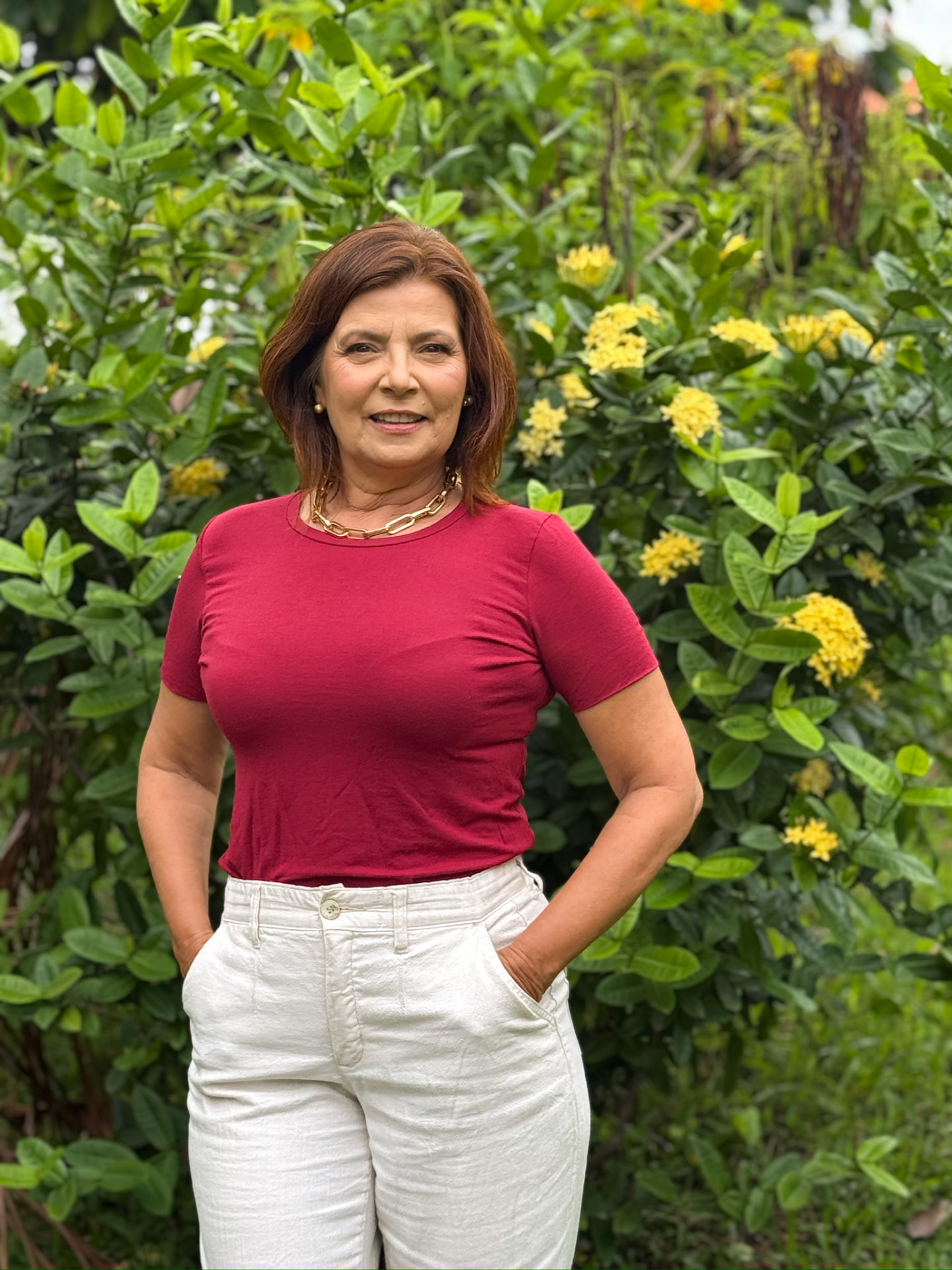 Adélia Pinheiro sorrindo em um jardim florido